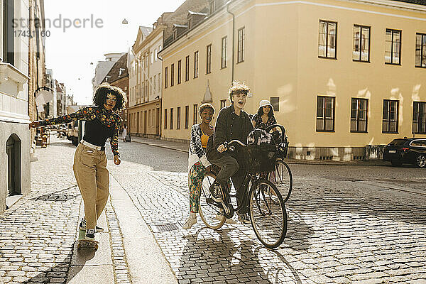 Fröhliche Freunde auf dem Fahrrad und Skateboard in der Stadt