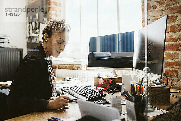 Weiblicher Manager beim Schreiben am Schreibtisch im Büro