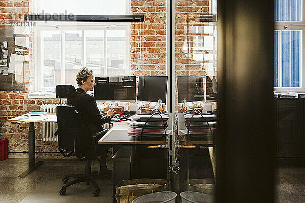 Weiblicher Manager  der einen Laptop benutzt  während er am Schreibtisch im Kreativbüro sitzt