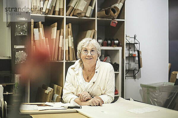 Lächelnde Handwerkerin lehnt sich im Büro über den Tisch