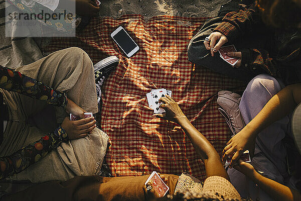 Gemischtrassige Freunde spielen Karten am Strand