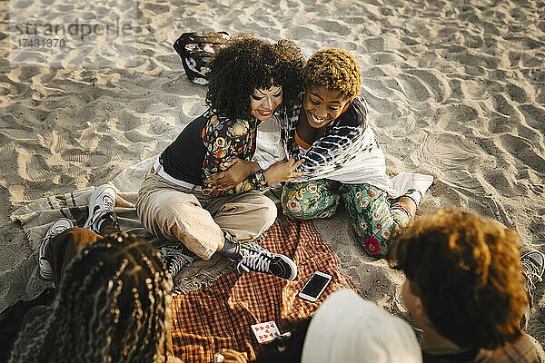 Lächelndes Mädchen im Teenageralter umarmt nicht-binären Freund am Strand