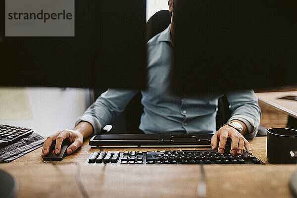 Geschäftsmann  der einen Computer benutzt  während er am Schreibtisch im Büro sitzt