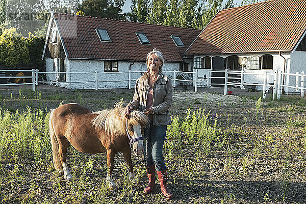 Porträt einer lächelnden älteren Frau mit Pony auf einem Bauernhof