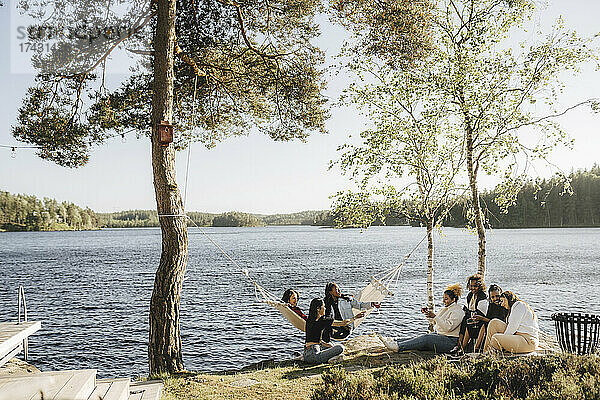Multirassische Freundinnen genießen am Seeufer an einem sonnigen Tag
