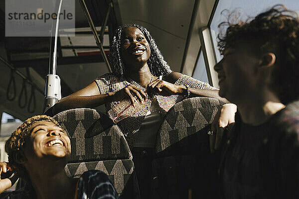 Glückliche multirassische LGBTQIA-Freunde im Bus an einem sonnigen Tag