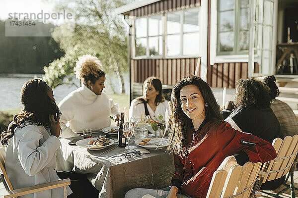 Porträt einer Frau mit Freundinnen beim Essen auf einer Party an einem sonnigen Tag