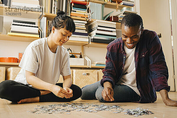 Lächelndes Paar spielt Puzzle auf dem Boden zu Hause