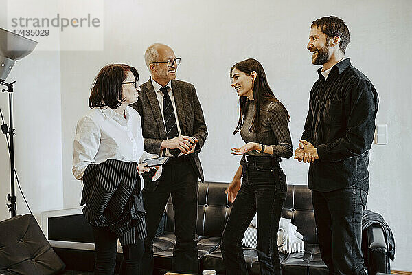 Lächelnde männliche und weibliche Investoren mit Programmierern  die in einem Meeting im Büro diskutieren