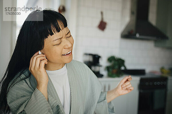 Fröhliche junge Frau singt beim Musikhören zu Hause