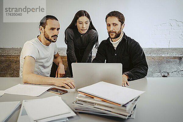 Männliche und weibliche Fachkräfte arbeiten an einem Laptop auf einem Tisch in einem Startup-Unternehmen