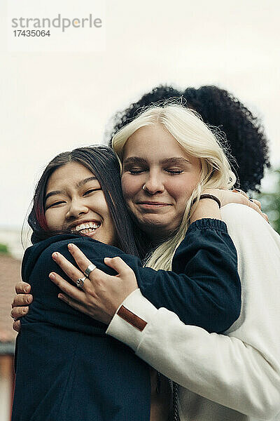 Lächelnde multirassische Freundinnen umarmen sich im Park