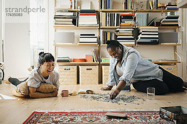 Glückliche Freundinnen spielen Puzzle auf dem Boden zu Hause