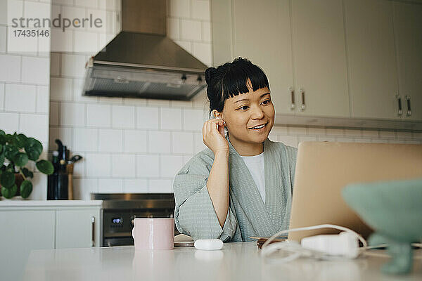 Lächelnde Frau  die einen Videoanruf über einen Laptop in der heimischen Küche führt
