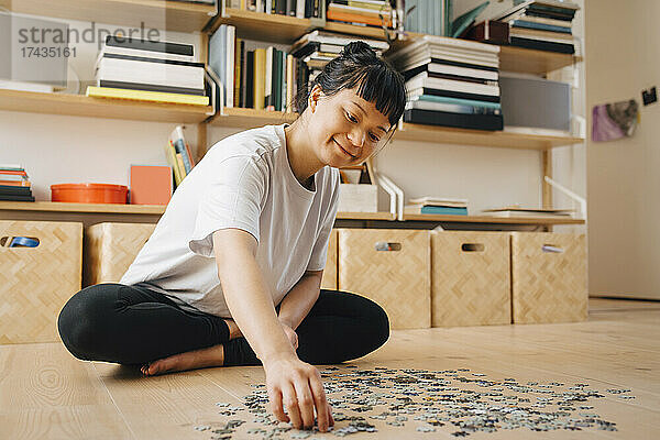 Lächelnde Frau spielt Puzzle im Wohnzimmer