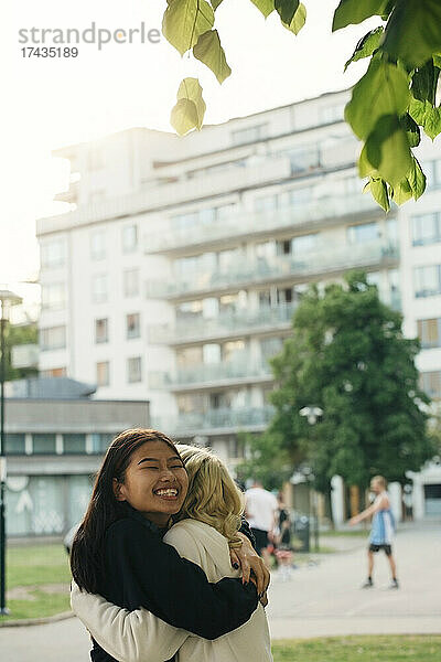 Lächelnde Freundinnen umarmen sich im Park