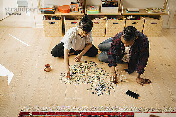 Multirassischer Mann und Freundin spielen Puzzle zu Hause