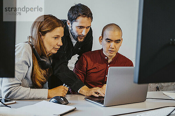 Weibliche und männliche Programmierer  die sich beim Programmieren auf einen Laptop im Büro konzentrieren