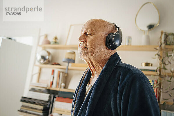 Älterer Mann hört zu Hause mit geschlossenen Augen über Kopfhörer Musik