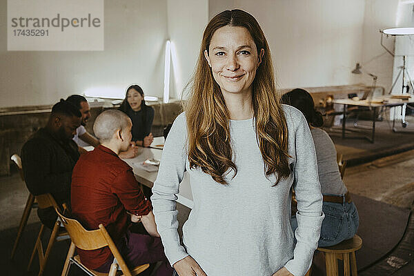 Porträt einer selbstbewussten Geschäftsfrau mit Kollegen im Hintergrund in einem Start-up-Unternehmen