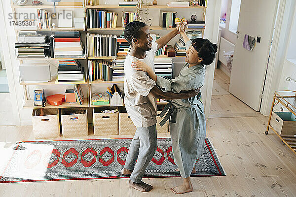 Lächelnde multirassische Paar tanzen zusammen im Wohnzimmer zu Hause