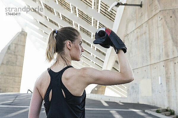 Ernsthafte Sportlerin lässt ihre Muskeln spielen  während sie einen Boxhandschuh trägt
