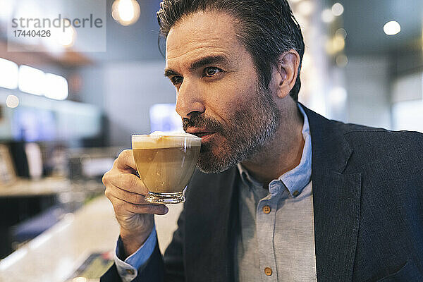 Reifer Geschäftsmann mit Haarstoppeln trinkt Kaffee im Hotel