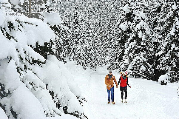 Frau geht im Winter mit Mann im Schnee spazieren
