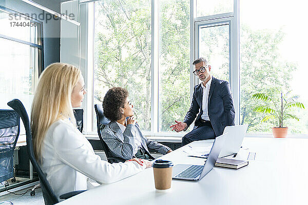 Weibliche Geschäftsleute hören männlichen Kollegen während eines Treffens im Büro zu