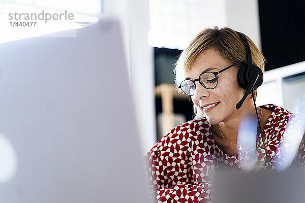 Kundendienstmitarbeiterin trägt Kopfhörer  während sie im Büro arbeitet