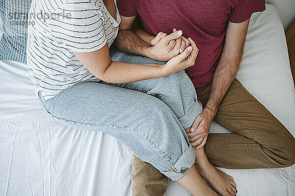 Mitte erwachsenes Paar mit gefalteten Händen sitzt auf dem Bett