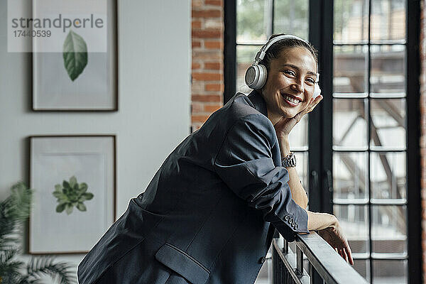 Glückliche Geschäftsfrau mit kabellosen Kopfhörern im Büro