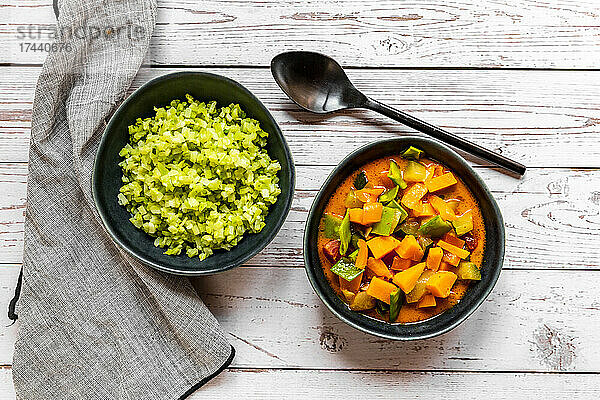 Studio shot of bowl of ready-to-eat low carb curry and chopped broccoli