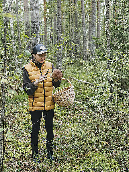 Frau mit Korb hält Pilze im Wald