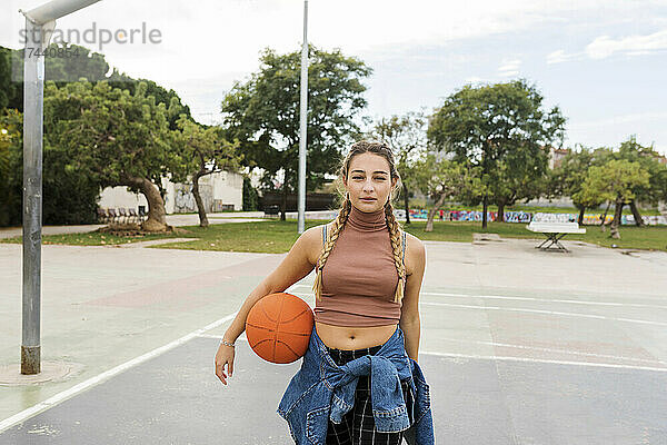 Junge Frau mit Basketball am Sportplatz