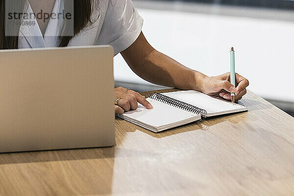 Berufstätige Frau schreibt mit Laptop Tagebuch im Restaurant