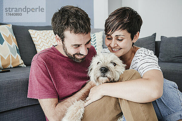 Mann und Frau spielen zu Hause mit Hund