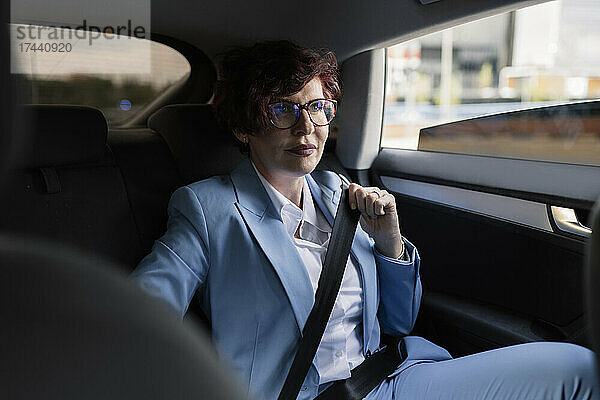 Professionelle Frau  die den Sicherheitsgurt anlegt  während sie im Auto sitzt