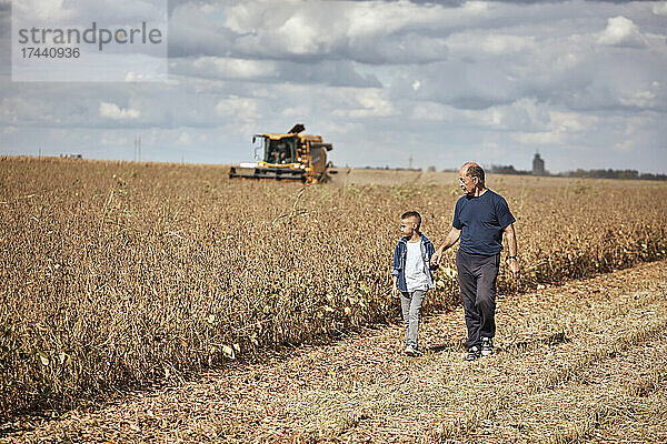 Großvater und Enkel gehen gemeinsam auf dem Bauernhof spazieren