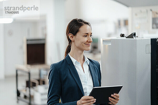 Lächelnde Geschäftsfrau mit digitalem Tablet in der Werkstatt