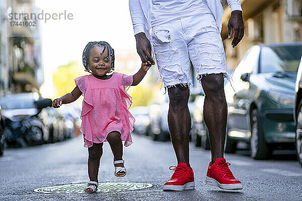 Mädchen hält die Hand ihres Vaters beim Gehen auf der Straße