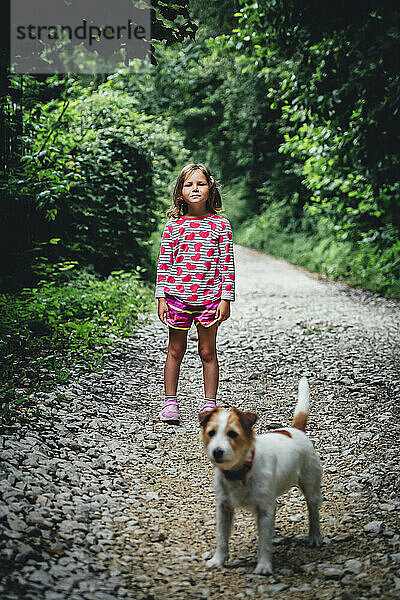 Mädchen steht mit Hund im Wald