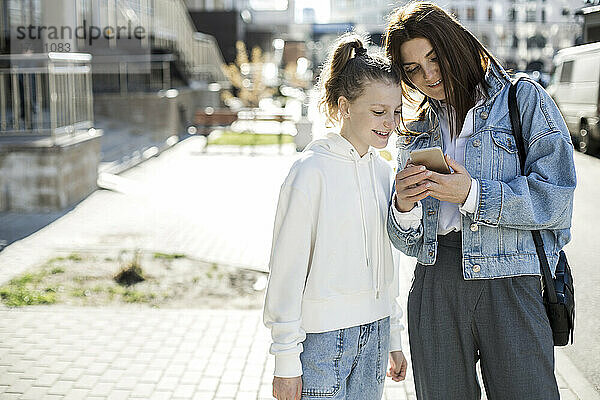 Mutter teilt Mobiltelefon mit Tochter auf der Stadtstraße