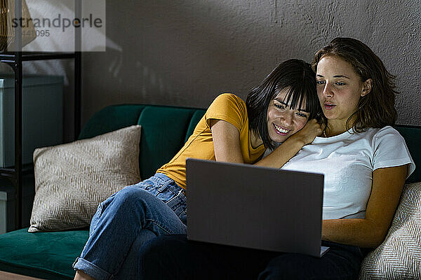 Junges lesbisches Paar teilt Laptop im Wohnzimmer