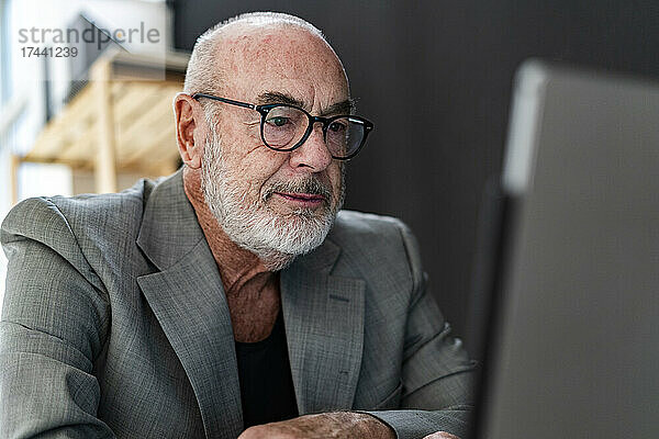 Leitender Geschäftsmann mit Brille und Laptop im Studio