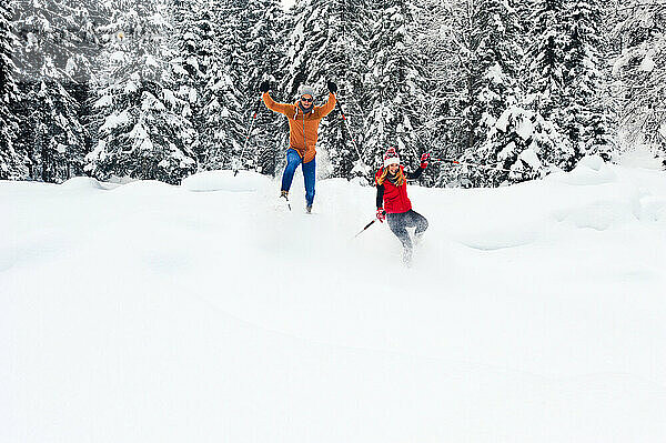 Mitte erwachsenes Paar mit Wanderstock beim Schneeschuhwandern im Winter