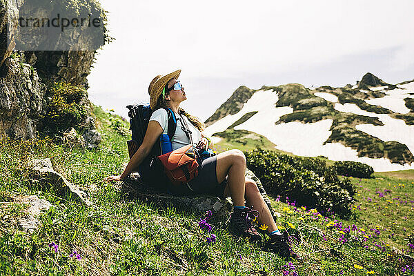 Wanderin mit Rucksack entspannt am Berg