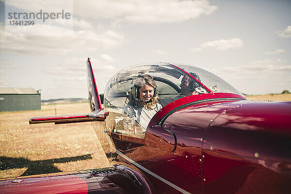 Lächelnde reife Frau  die an einem sonnigen Tag ein Flugzeug steuert