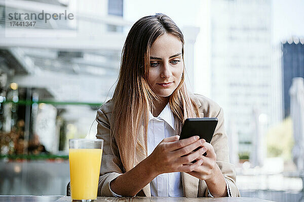 Geschäftsfrau benutzt Smartphone auf Caféterrasse