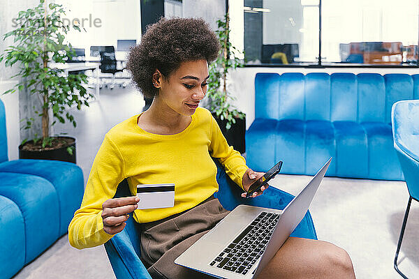 Afro-Geschäftsfrau leistet Online-Zahlung per Kreditkarte in der Bürolobby